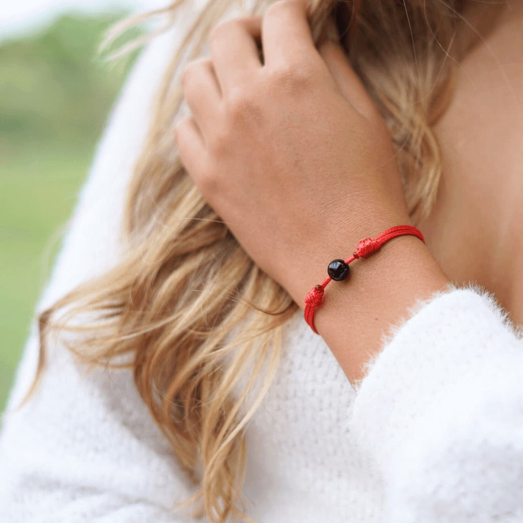 Luck Strings -A woman's wrist adorned with the Protection Black Tourmaline Red String Adjustable Bracelet 